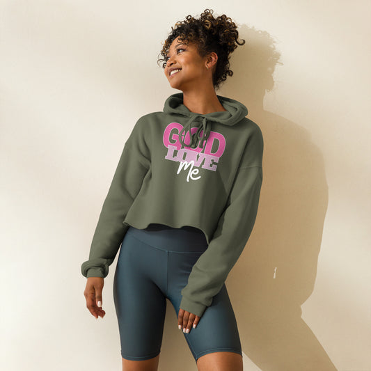 Woman wearing a green hoodie with pink text : God Love Me and dark shorts on a plain background